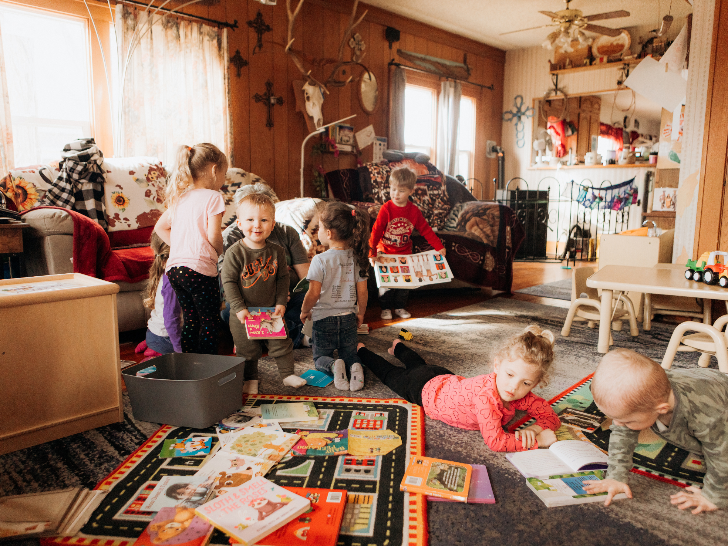 Niños de un programa de cuidado infantil familiar que están explorando con entusiasmo los libros.